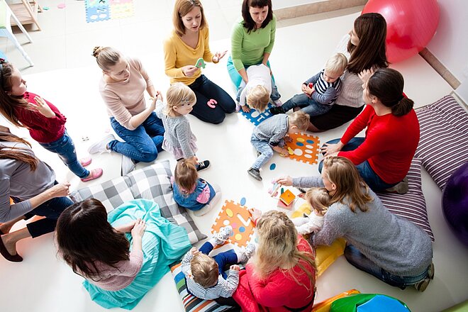 Eine Gruppe von Frauen und Kindern sitzt auf dem Boden im Mütterzentrum der AWO in Mönchengladbach.